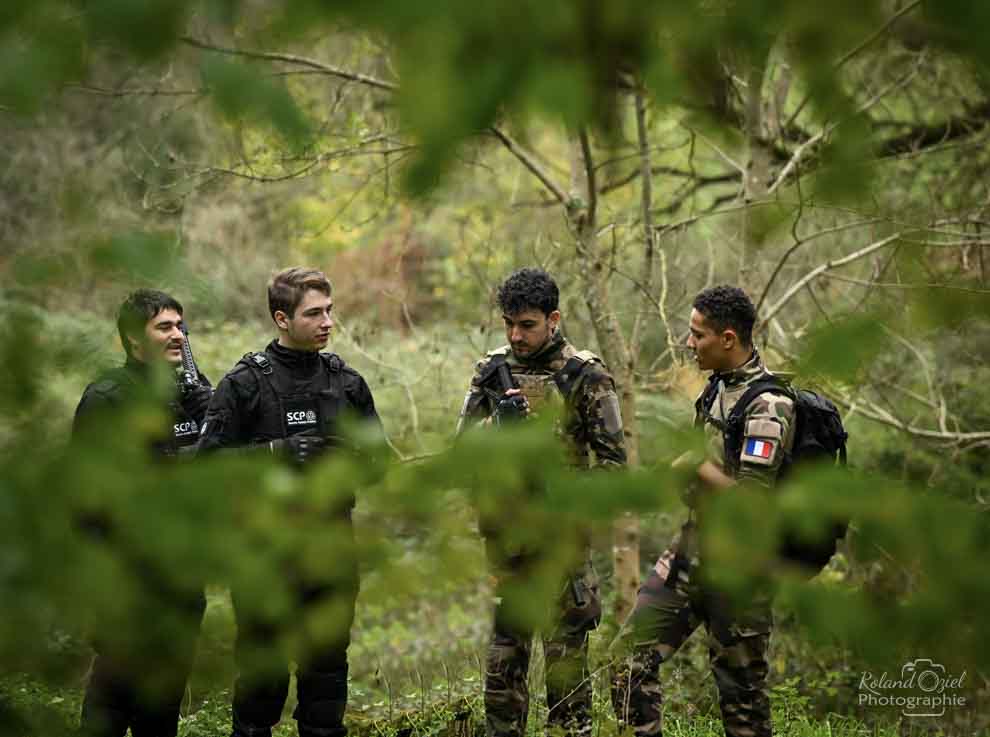 Photographe ayant pris en photo le groupe pratiquant le airsoft au travers des arbres