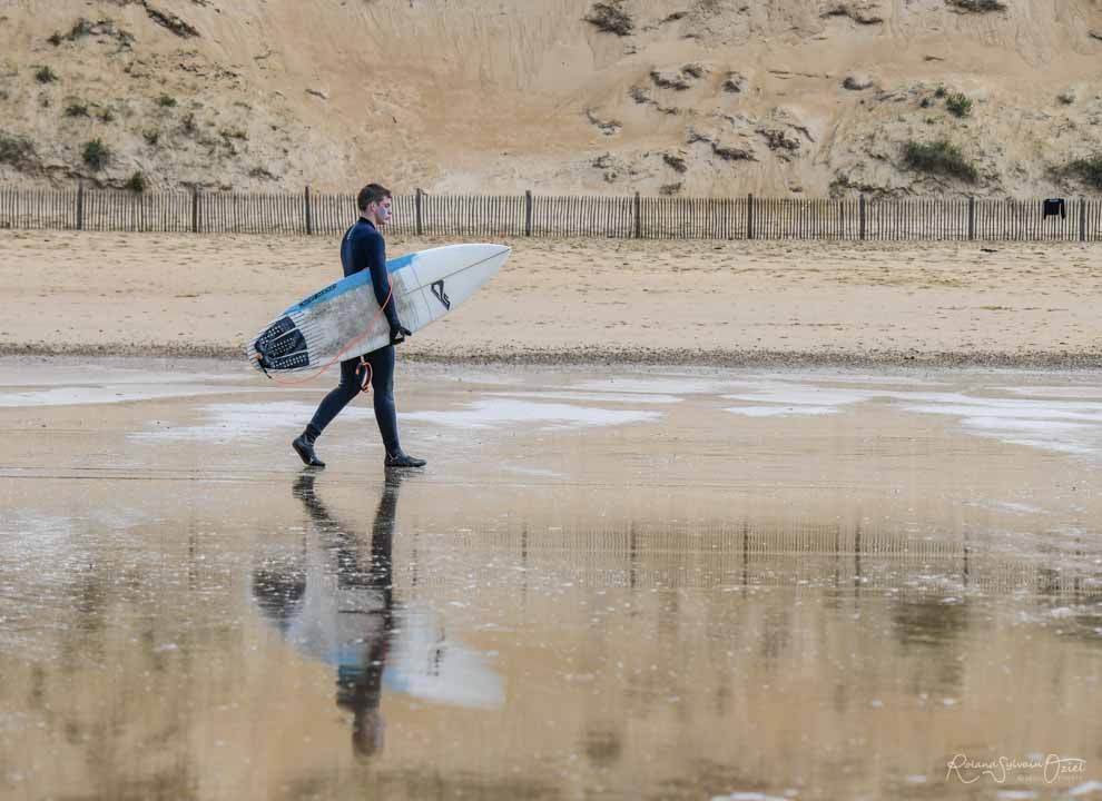 Photo d&apos;un surfeur qui marche sur la plage