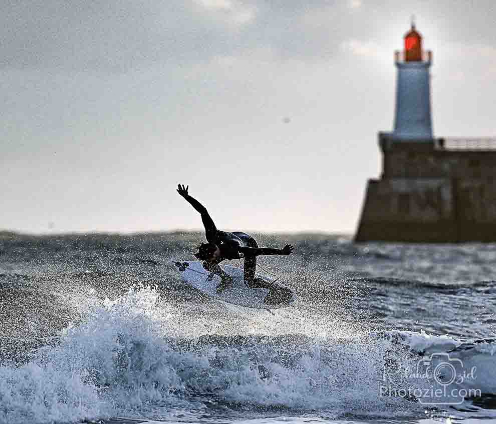 Jeune surfeur en photo devant le phare des sables